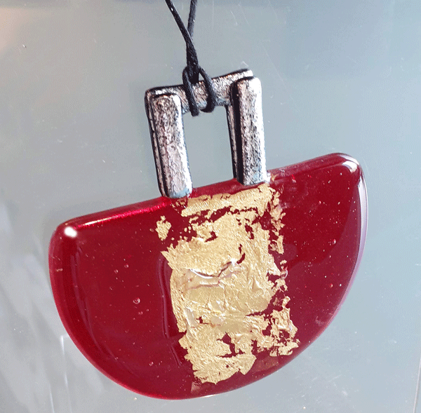 Vista del gioiello di profilo: Abbondanza dal sole, in vetro di Murano Rosso rubino e inserti in foglia d'oro